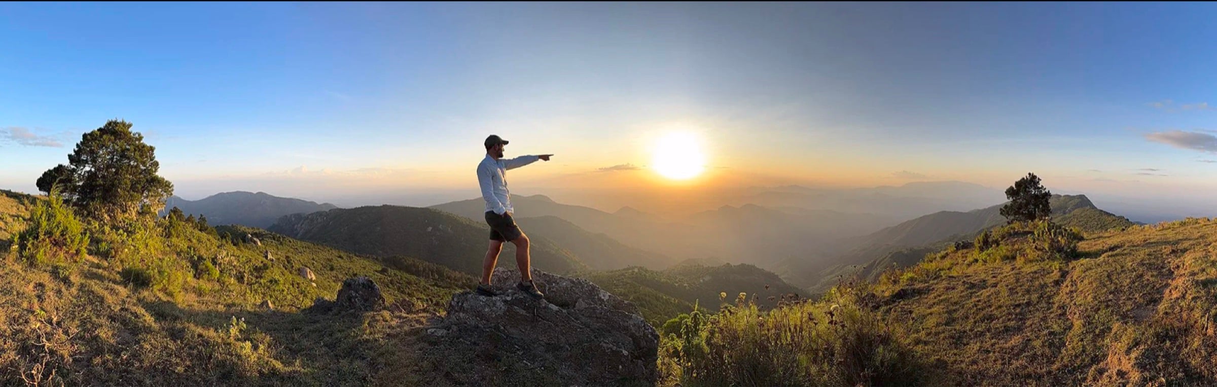 Austin Mann pointing toward the sunset over the Kenyan highlands