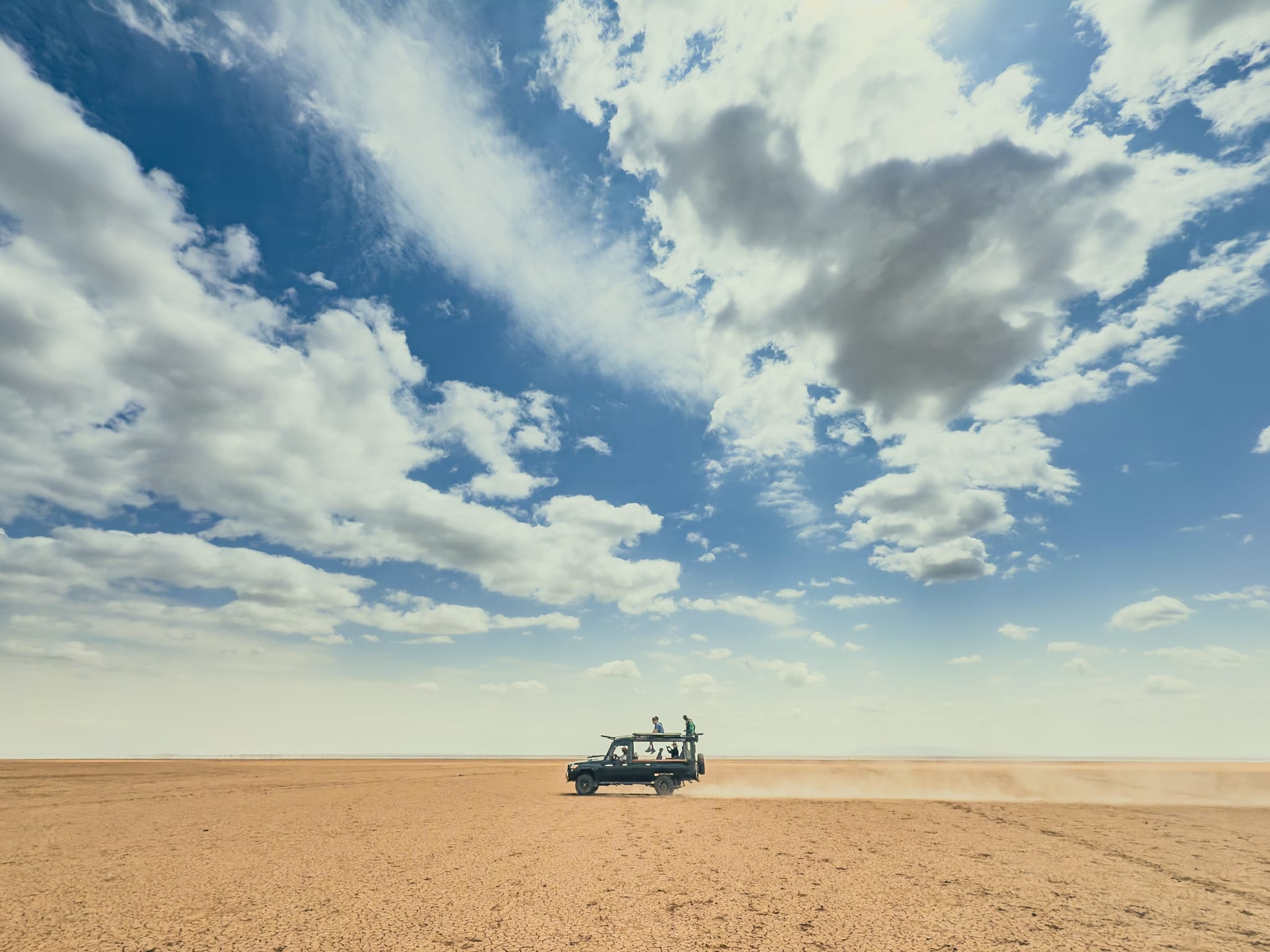 The cruiser crossing a dry lake bed under big clouds