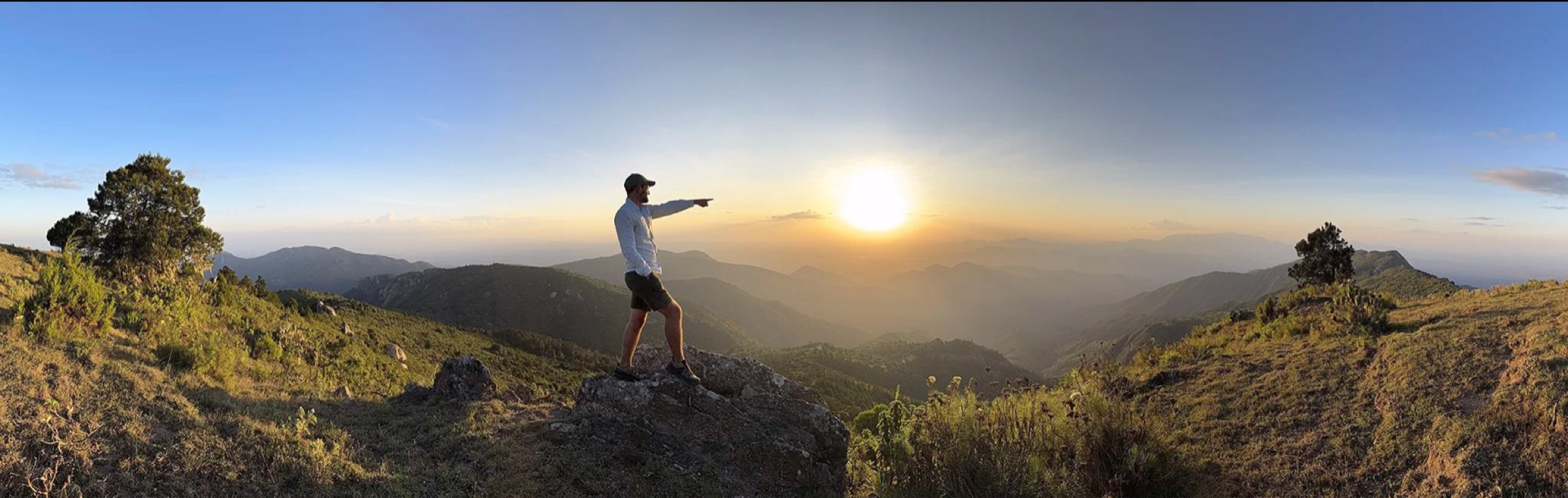 Austin Mann pointing toward the sunset over the Kenyan highlands