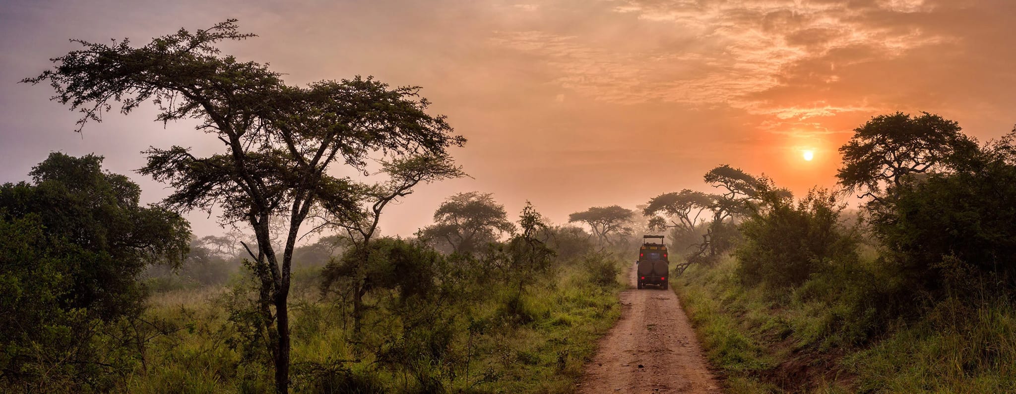 A safari cruiser on a dirt track at sunrise, Rwanda