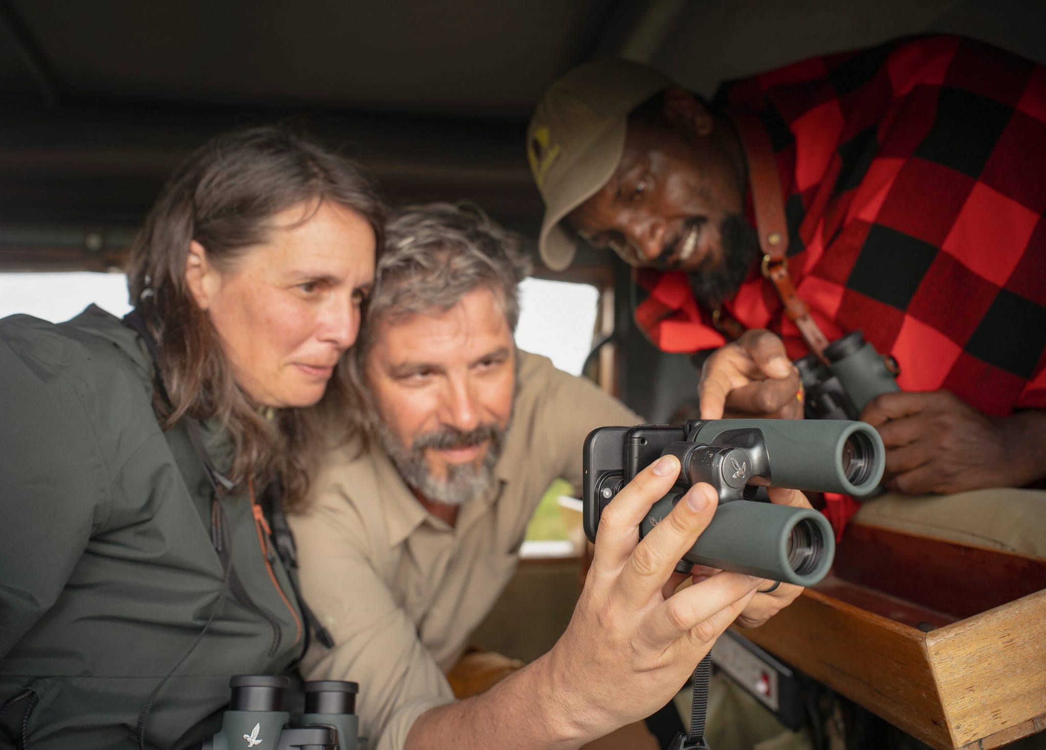 Guests and a Maasai guide checking a frame on the iPhone through Swarovski binoculars