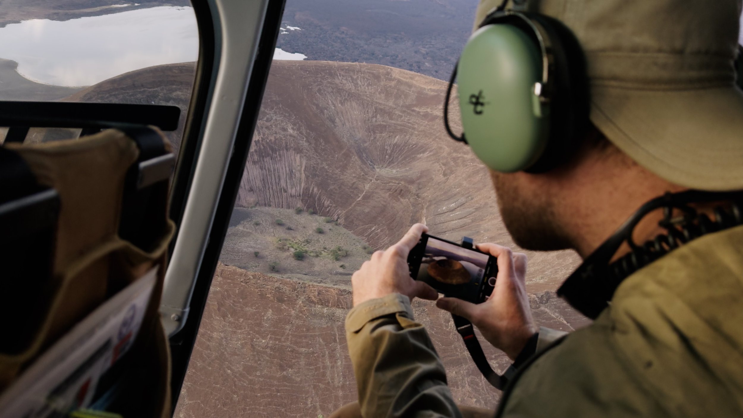 Austin Mann photographing Nabuyotum Crater on iPhone from a helicopter in northern Kenya